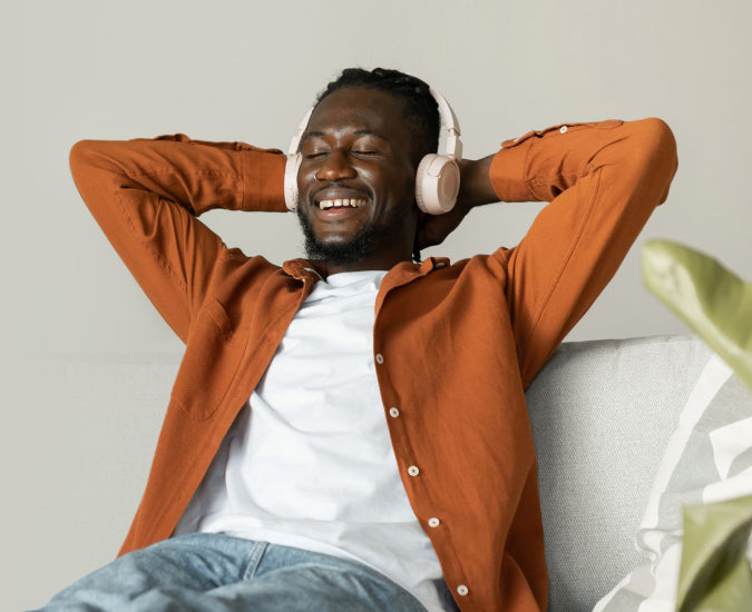 A smiling man wearing headphones, leaning back with his eyes closed.